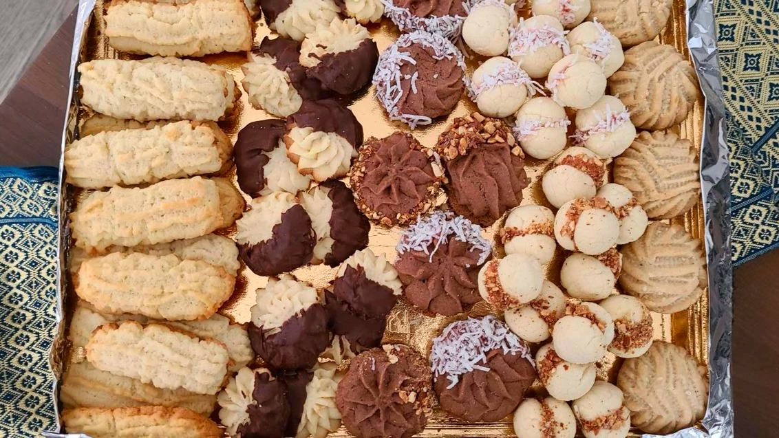 Round platter of assorted Middle Eastern desserts — Kahk with powdered sugar, chocolate-dipped petit four, different shaped Ghorayeba, Laksheir and Nashader biscuits
